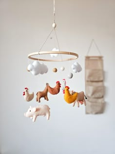 a mobile with animals hanging from it's sides and clouds above them, in front of a white wall