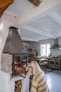 a woman is looking at the fire in an oven that has been built into the wall