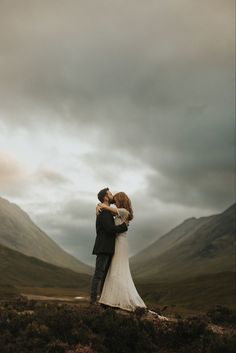 a bride and groom embracing in the mountains