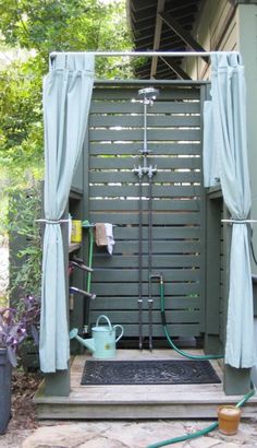 an outdoor shower with curtains and hoses attached to it