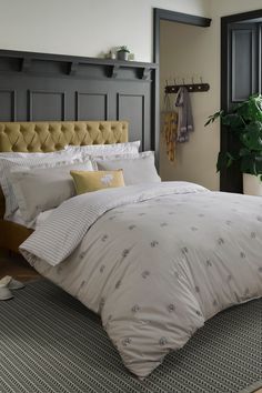 a bedroom with a large bed and potted plant on the floor next to it