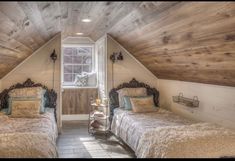 two beds in a small room with wooden walls and ceilings, one is made from wood planks