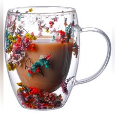 a glass cup filled with liquid and colorful flowers on the inside is full of butterflies