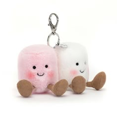 two small stuffed animals sitting next to each other on a white background, one is pink and the other is white