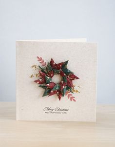 a christmas card with an ornament on the front and red leaves on the back