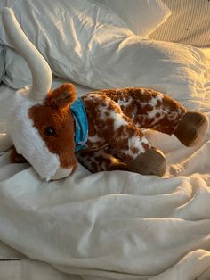 a brown and white stuffed animal laying on top of a bed