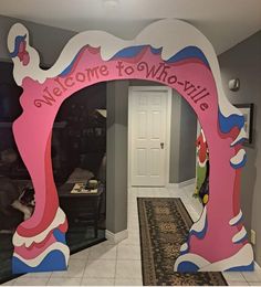 the entrance to a home decorated with pink and blue decorations, including a welcome sign