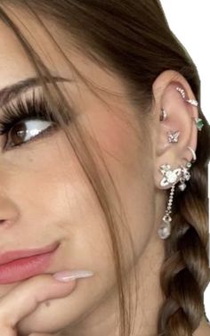 a close up of a person with ear piercings on their ears and hands near her face