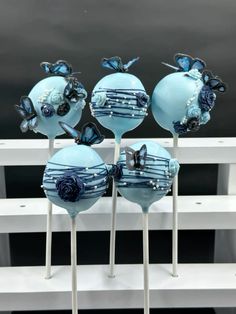 four blue cake pops with butterflies on them