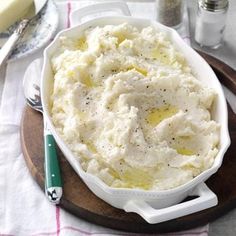 mashed potatoes in a white dish on a wooden platter