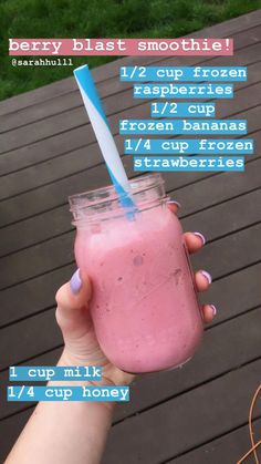 a person holding a pink smoothie in a mason jar