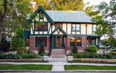 a large house with green trim and windows on the front porch is surrounded by greenery