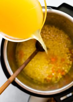 a pot filled with soup next to a wooden spoon