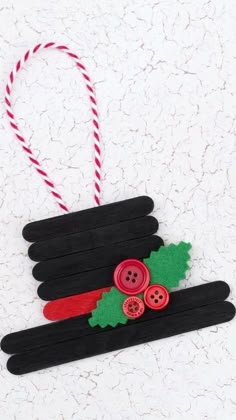 an ornament made out of popsicle sticks with buttons and holly leaves on them