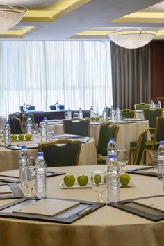 tables and chairs are set up with water bottles, glasses, and apple slices on them