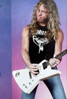 a man with long hair holding a white guitar in front of a purple and blue background