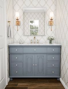 a bathroom with a blue vanity and gold fixtures on the wall, along with a mirror above it