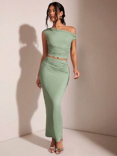 a woman in a green two piece dress with one shoulder cut out, and the other half