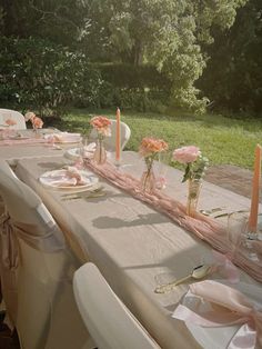 a long table set up with pink flowers and candles for a wedding or special event