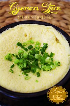 korean steamed egg soup with green onions in a black bowl on a wicker table