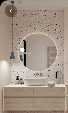 a bathroom with a large round mirror above the sink and lights hanging from the ceiling