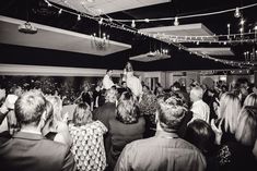 black and white photograph of people dancing in a club with lights strung above the dance floor