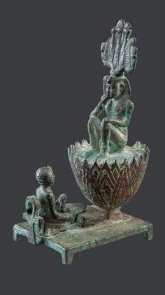 a statue is sitting on a table next to a vase with a man in it