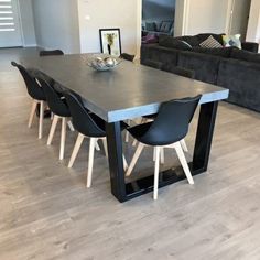 a dining room table with black chairs and a gray couch in the backround