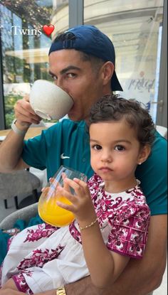 a man is holding a child and drinking orange juice