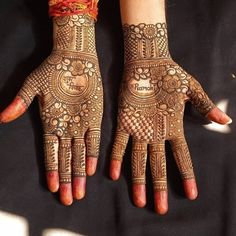 two hands with henna designs on them and one hand is decorated with an orange ribbon