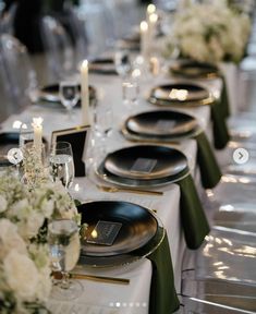 the table is set with black and white plates, silverware, and flower centerpieces