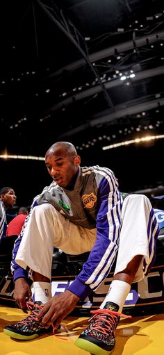 a man sitting on top of a basketball court next to a pair of black shoes