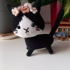 a crocheted black and white cat next to a potted plant