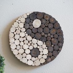 a yin - yang sign made out of wood logs on the wall next to a potted plant