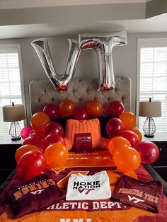 an orange and red bed with balloons on it in front of the headboard is decorated with letters that spell i love virginia