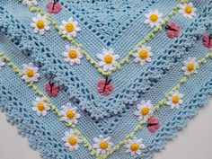 a crocheted blanket with flowers and butterflies on the edges is laying on a white surface