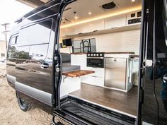 the interior of a camper van with its door open and kitchen in the back