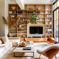 a living room filled with furniture and a flat screen tv mounted on a wall next to a window