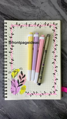 three pens sitting on top of a notebook