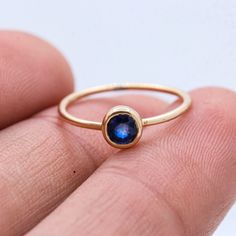 a hand holding a gold ring with a blue gemstone in it's center