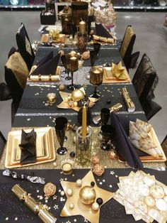 a table set with black and gold plates, napkins and place settings for an event