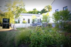 the house is white and has lots of plants in front of it, including flowers