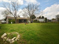 a yard with grass and rocks in front of a house on the other side of it