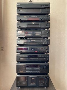 a stack of stereos sitting on top of each other in front of a wall