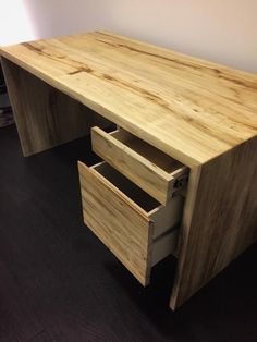 a wooden desk with two drawers on the bottom and one drawer open in front of it