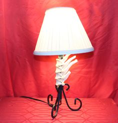 a lamp that is on top of a red cloth covered table with a white lampshade