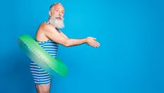 an old man with a white beard in a blue and white striped swimsuit holding a green raft