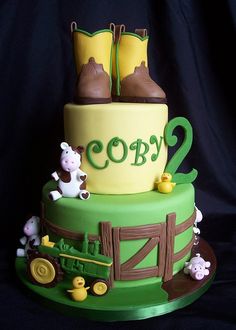 a green and yellow cake with farm animals on it's sides, including boots