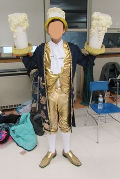 a man dressed in gold and white holding two large vases with flowers on them