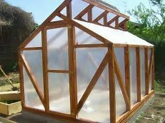 a small wooden greenhouse sitting in the middle of a yard